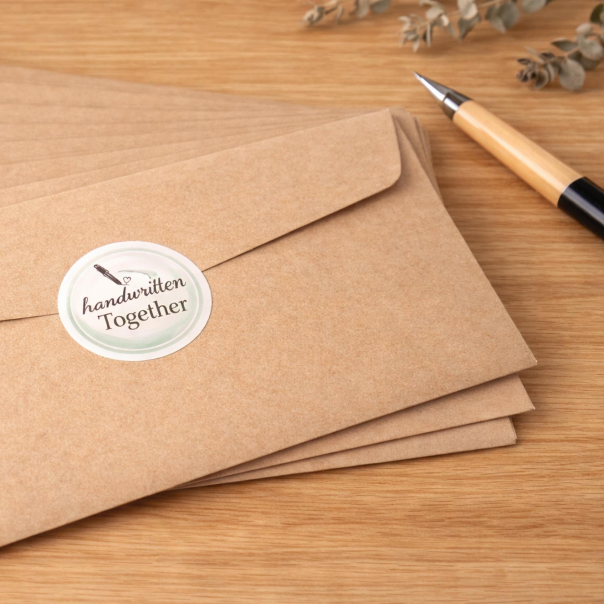 A fanned-out stack of textured brown Kraft paper envelopes resting on a light wooden desk, showcasing a rustic and natural stationery style.